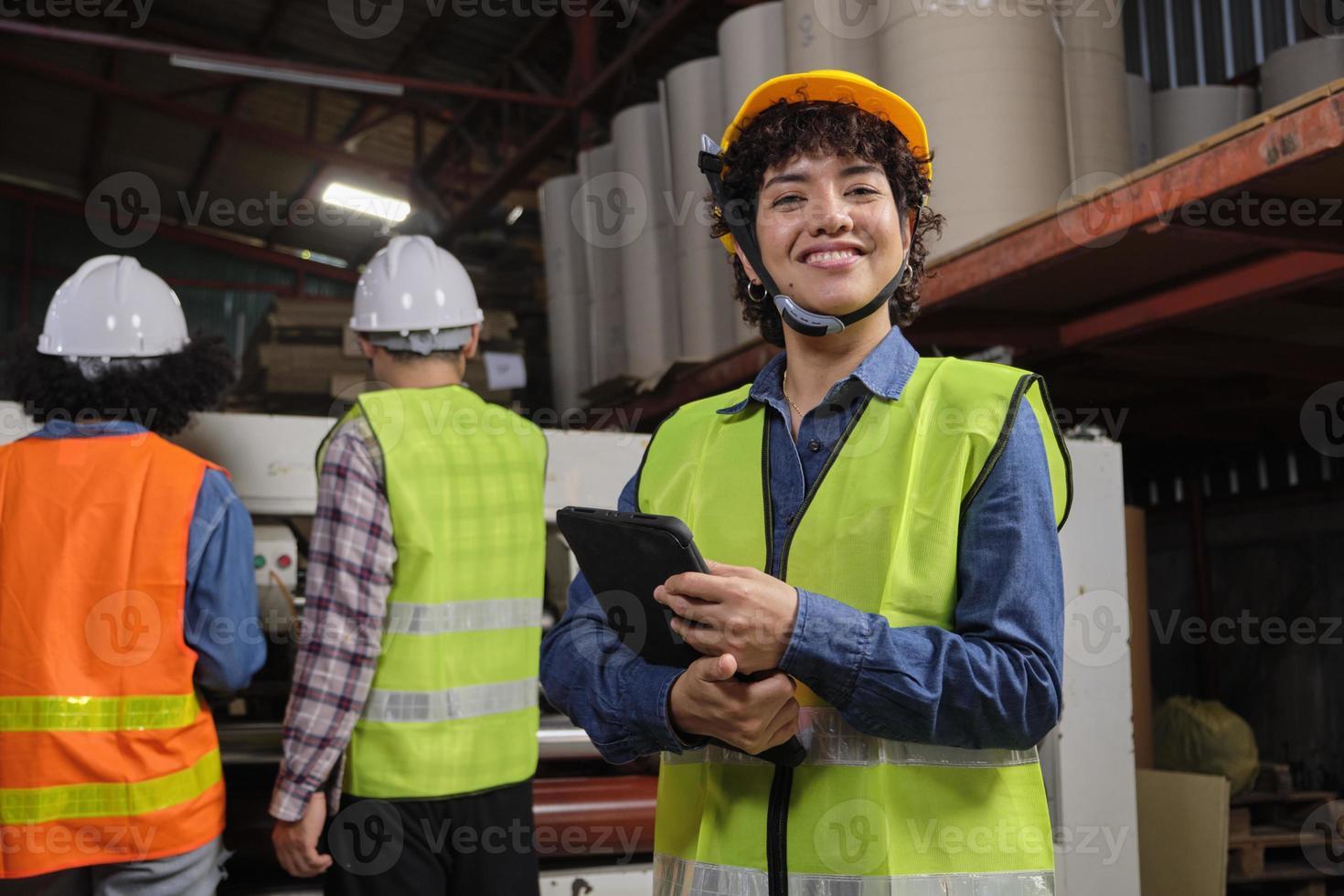 Portrait of safety uniform female engineer worker and hard hat with tablet looks at camera, happy smile and cheerful, industry jobs success, achievement, professional technician manufacture factory. photo