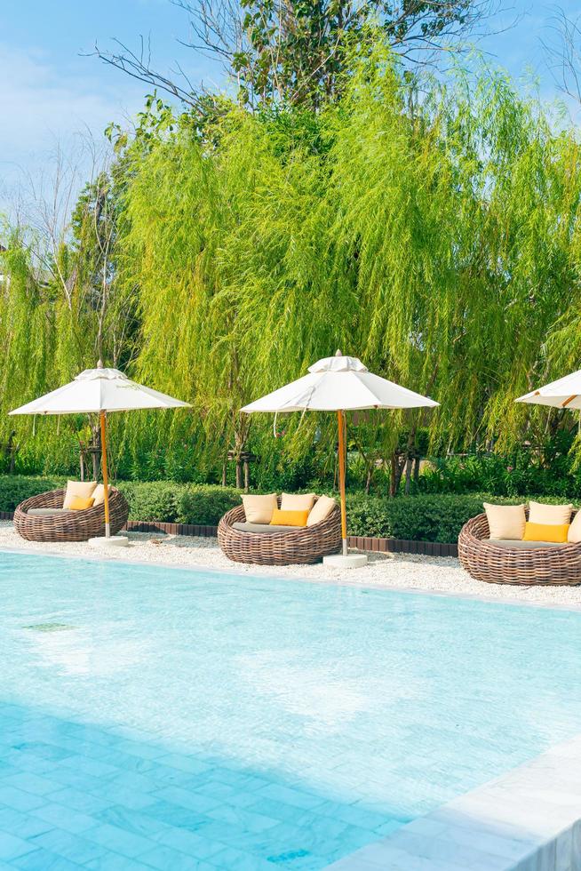 outdoor patio chair with pillow and umbrella around swimming pool photo