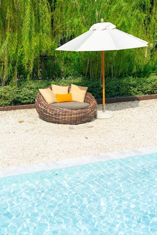 outdoor patio chair with pillow and umbrella around swimming pool photo