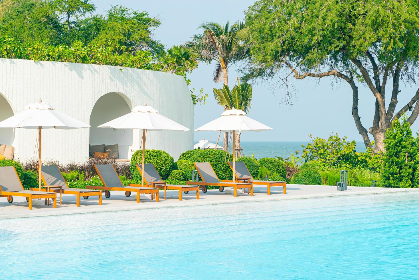 sombrilla con cama piscina alrededor de la piscina con fondo de mar océano foto