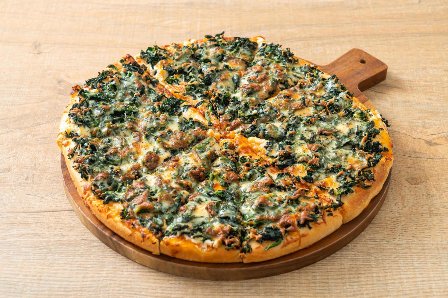Pizza de espinacas y queso en bandeja de madera foto