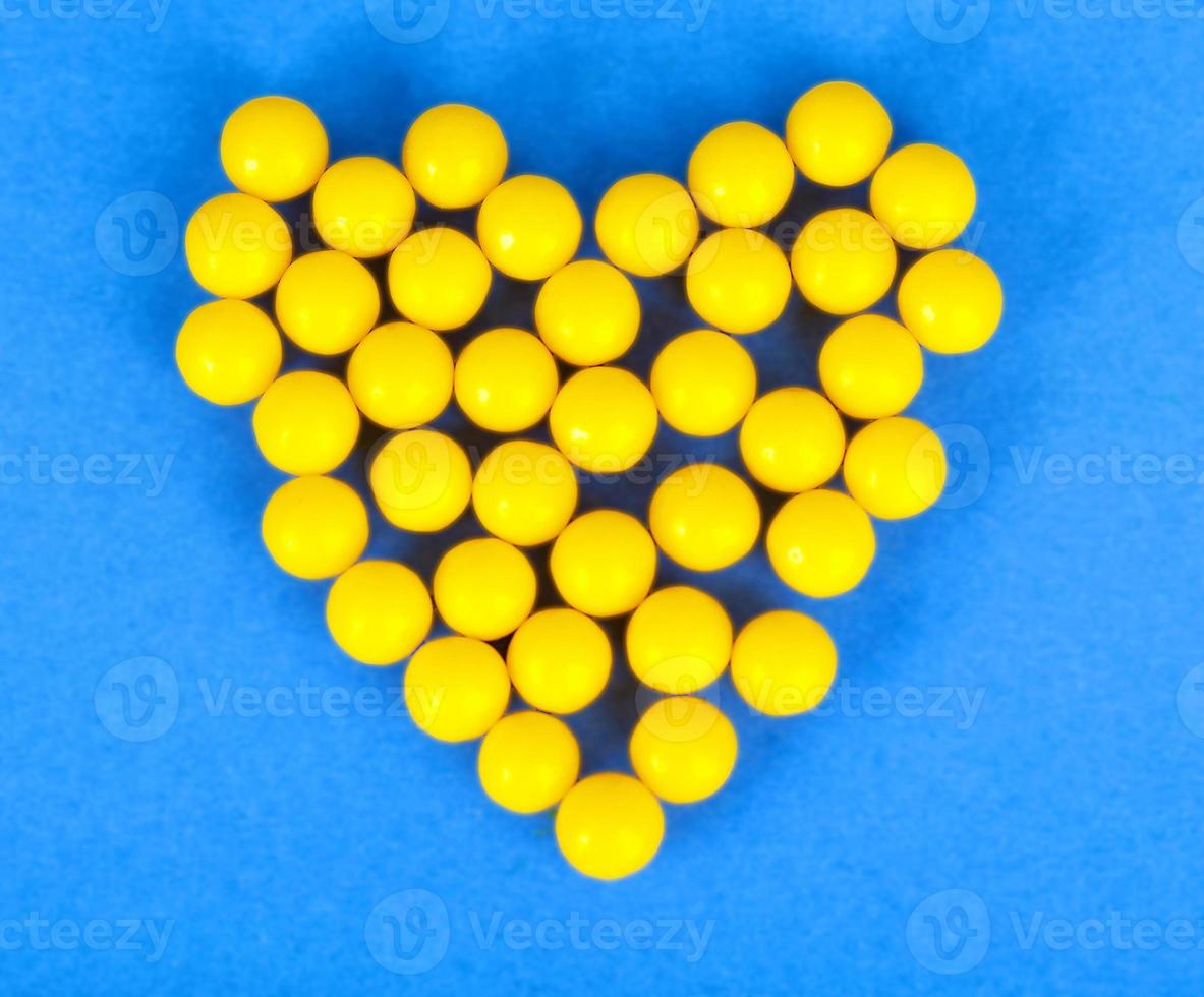 pequeñas píldoras amarillas redondas farmacéuticas médicas, vitaminas, medicamentos, antibióticos en forma de corazón foto