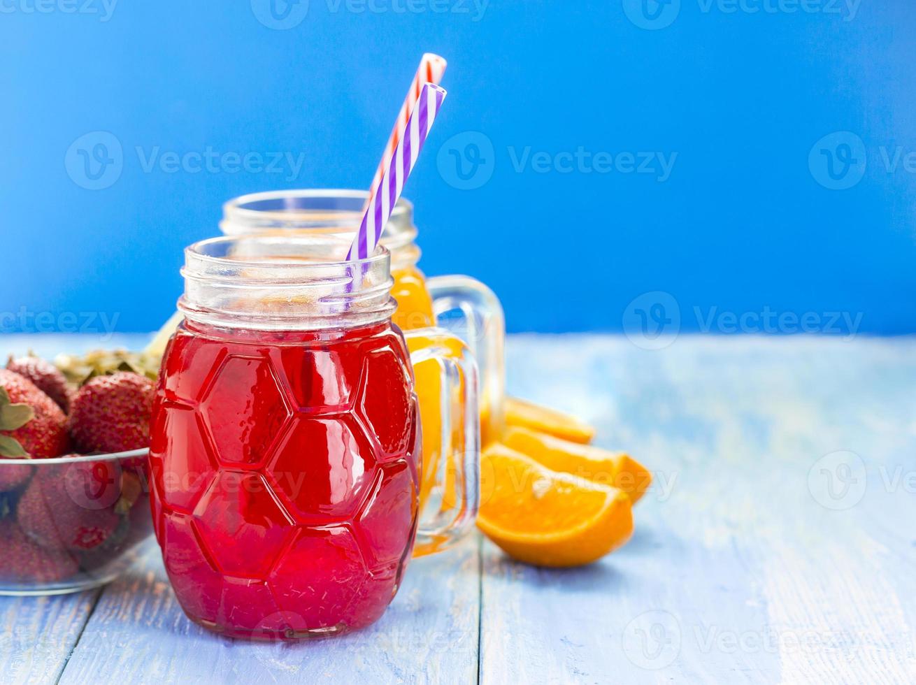 Batido de piña y fresa fresca en vasos con frutas sobre un fondo rústico de madera azul foto