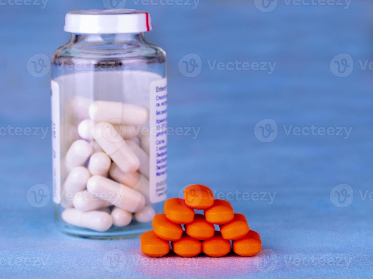 Group of red medical pills and bottle with white pills photo