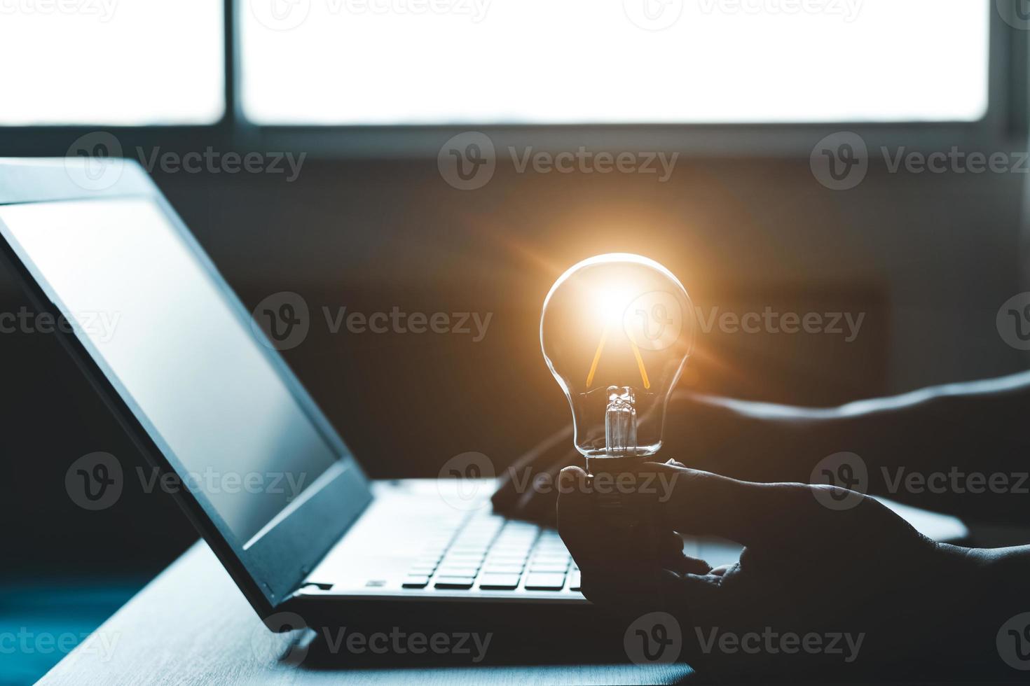 Hand holding a light bulb and working on a laptop computer, Concept of inspirational ideas creativity and technological innovation of the future. photo