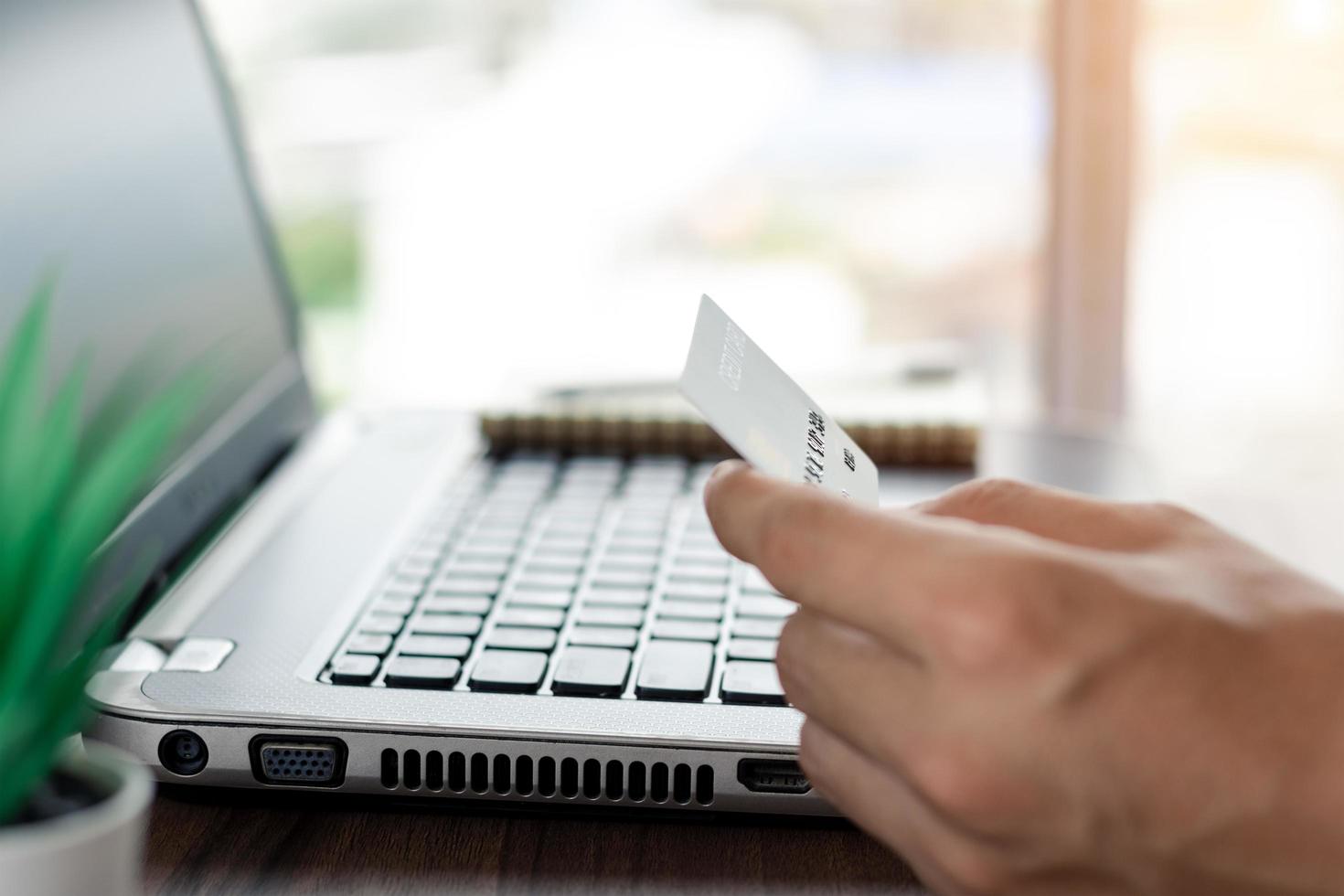 Businessman hand holding mock up credit card with using laptop for online shopping while making orders at home. business, lifestyle, technology, ecommerce, digital banking and online payment concept. photo