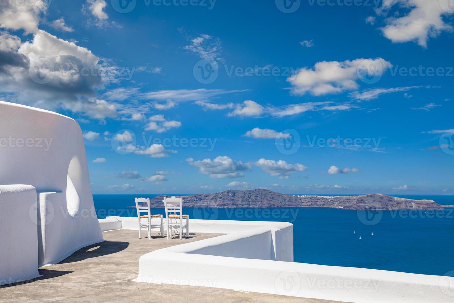 Two chairs on the terrace with sea views. Santorini island, Greece. Travel and vacation background. Best in travel landscape for romantic couple or honeymoon destination. Fantastic location and view photo