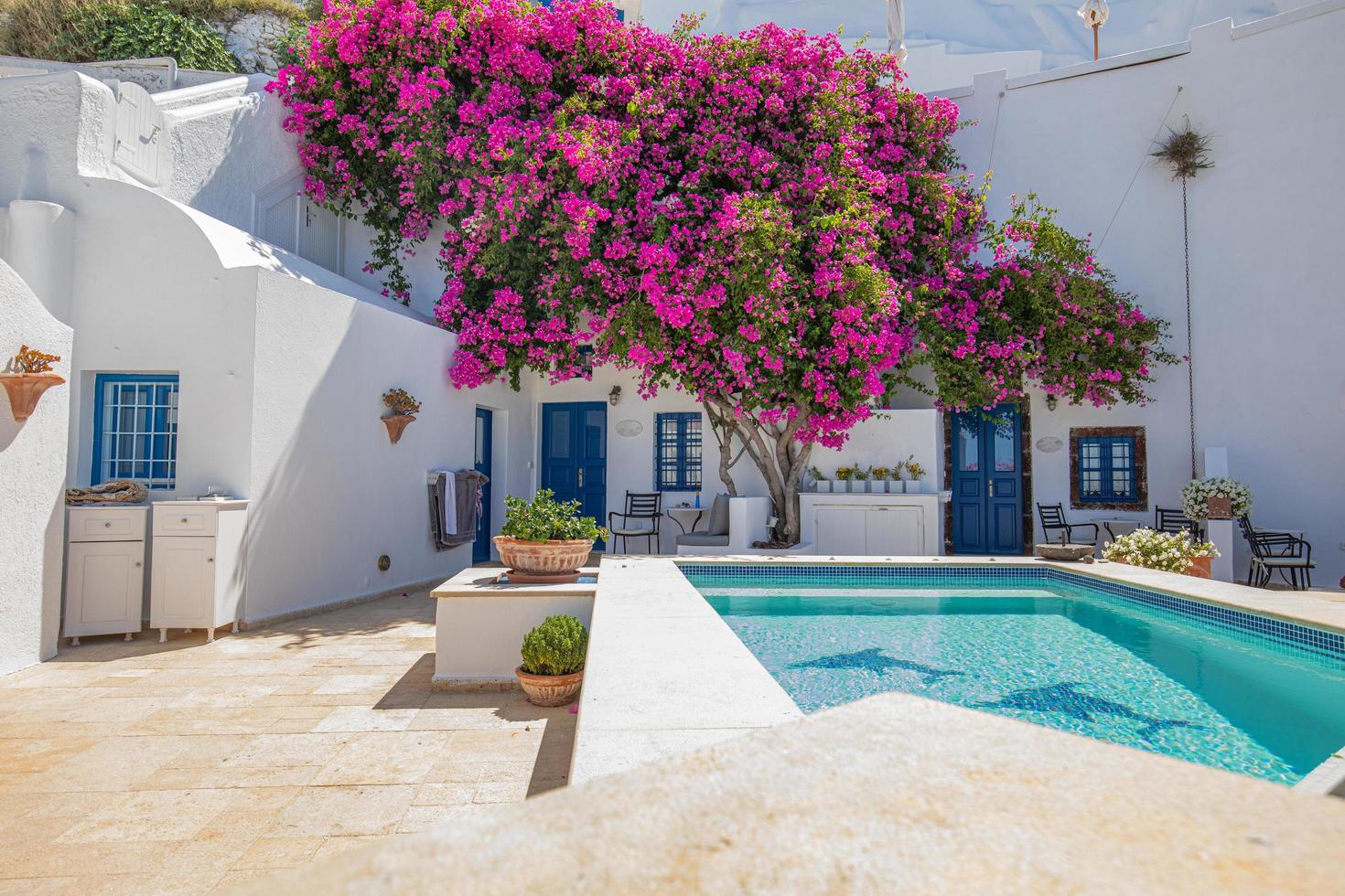 25.07.21 Santorini, Greece landscape, pool caldera view with flowers blue doors. Romantic couple destination with sunny sky, wonderful summer hotel resort travel vacation holiday. Inspire destination photo