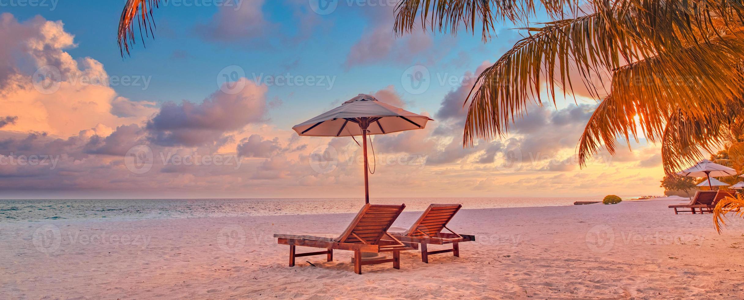 Beautiful panoramic nature. Tropical beach sunset as summer island landscape with chairs umbrella palm leaves calm sea shore, coast. Luxury travel panoramic destination banner for vacation or holiday photo