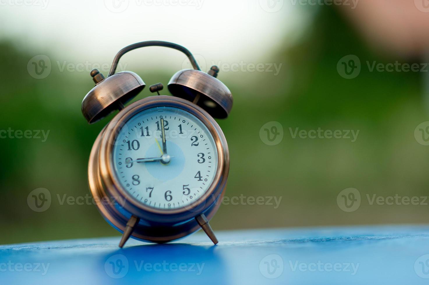 imagen de reloj de alarma dorada colocada en una mesa azul, concepto puntual de fondo verde con espacio de copia foto