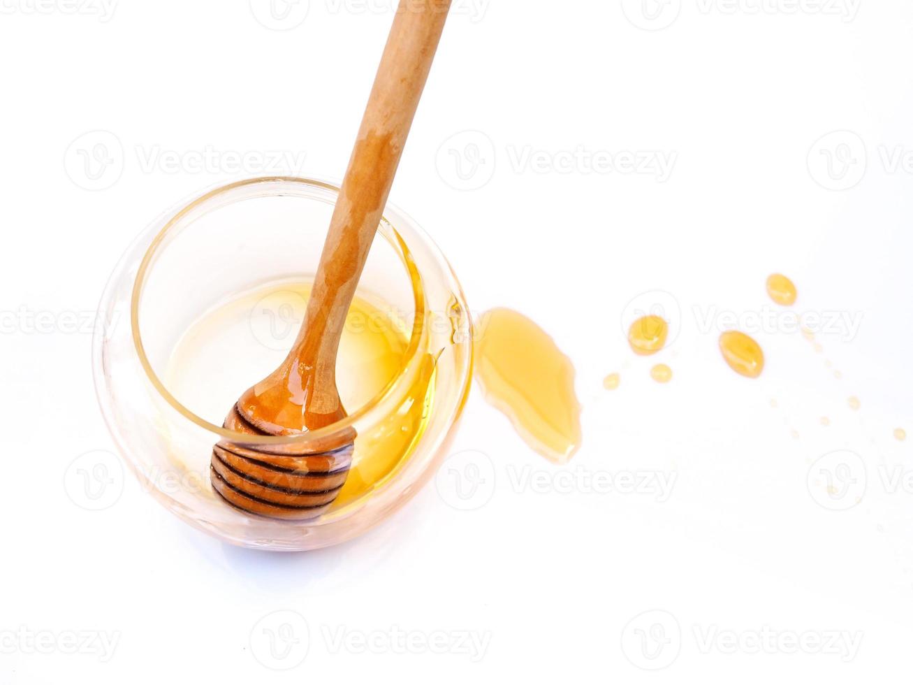 Top view of honey stick in empty honey glass jar with stain of honey isolated on white background. photo