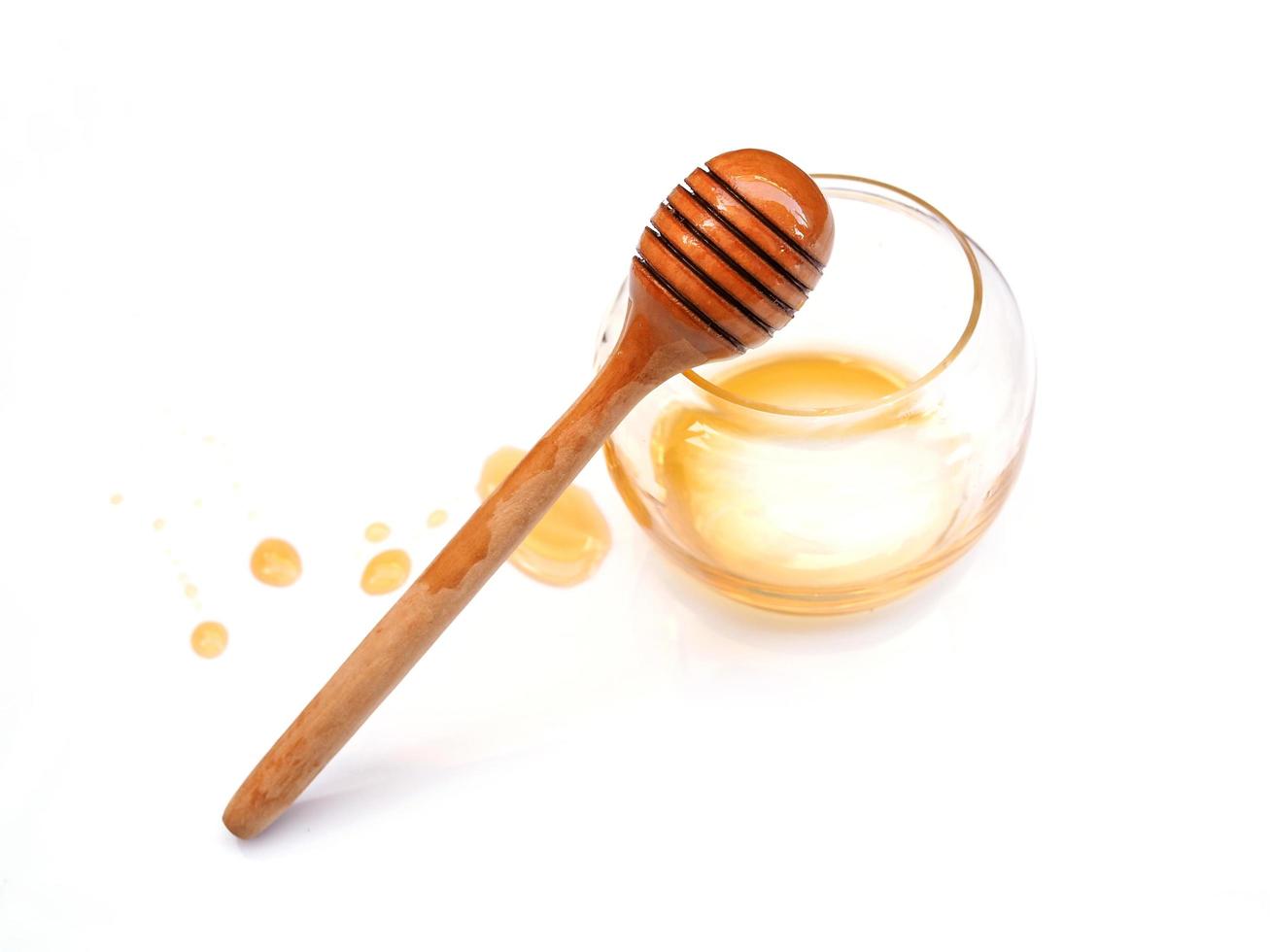 Top view of honey stick in empty honey glass jar with stain of honey isolated on white background. photo