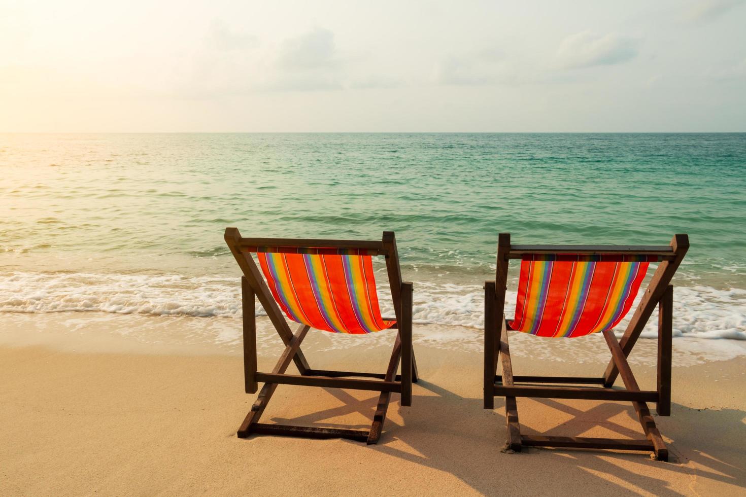 Two beach chairs on the sand beach with the light of the sun photo