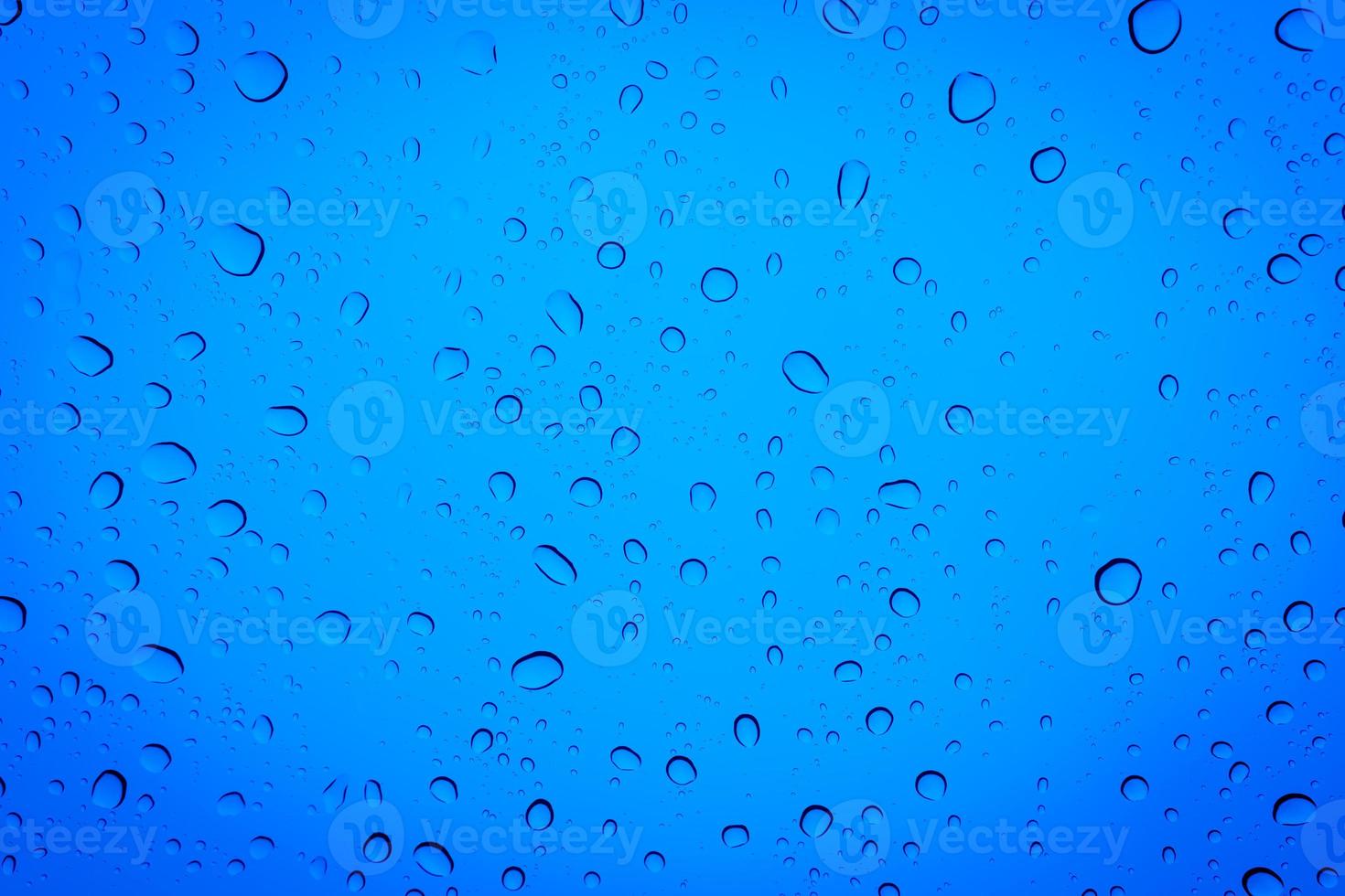 Drops of water on a blue glass, abstract blue background. photo