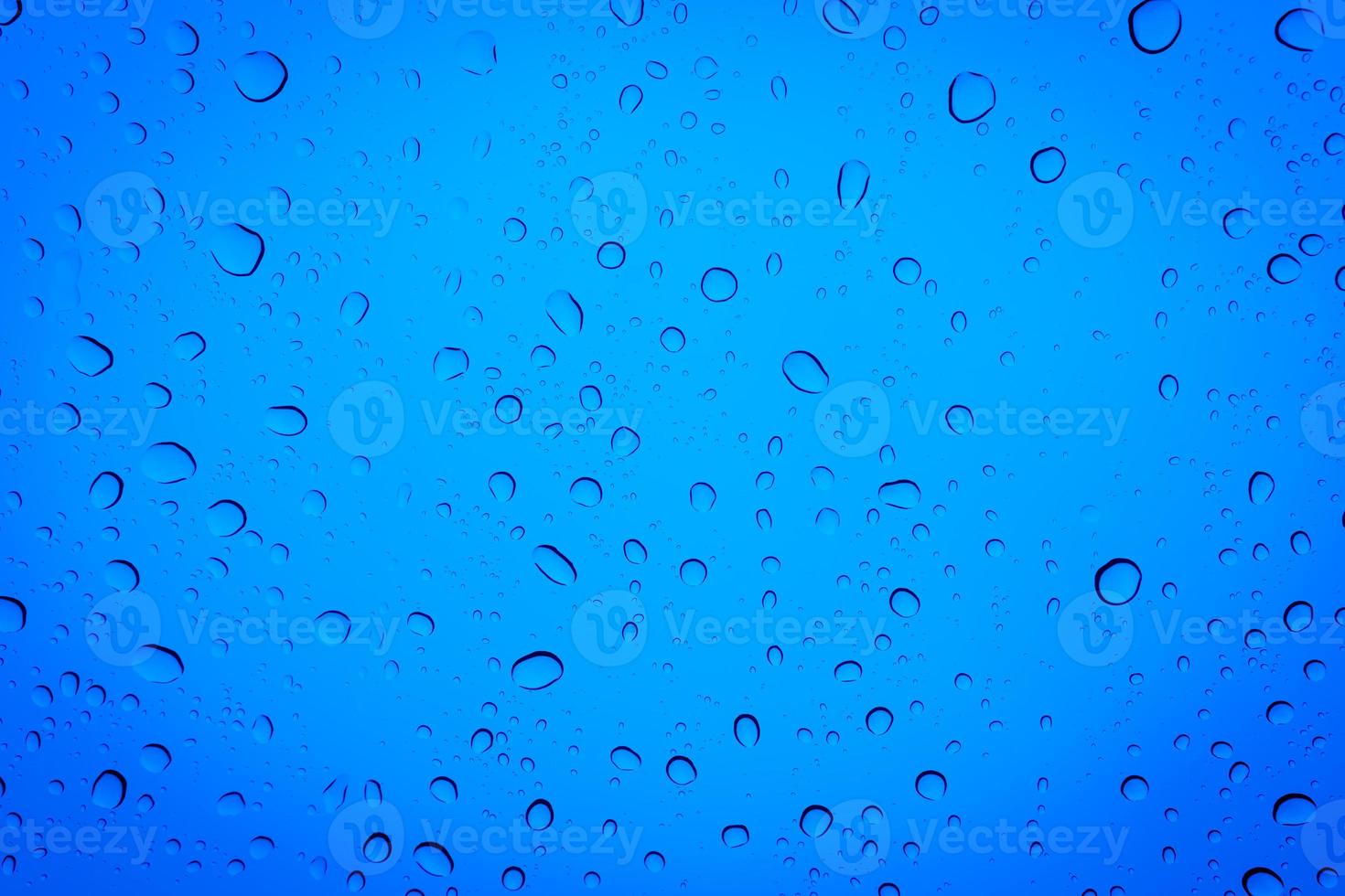 Drops of water on a blue glass, abstract blue background. photo