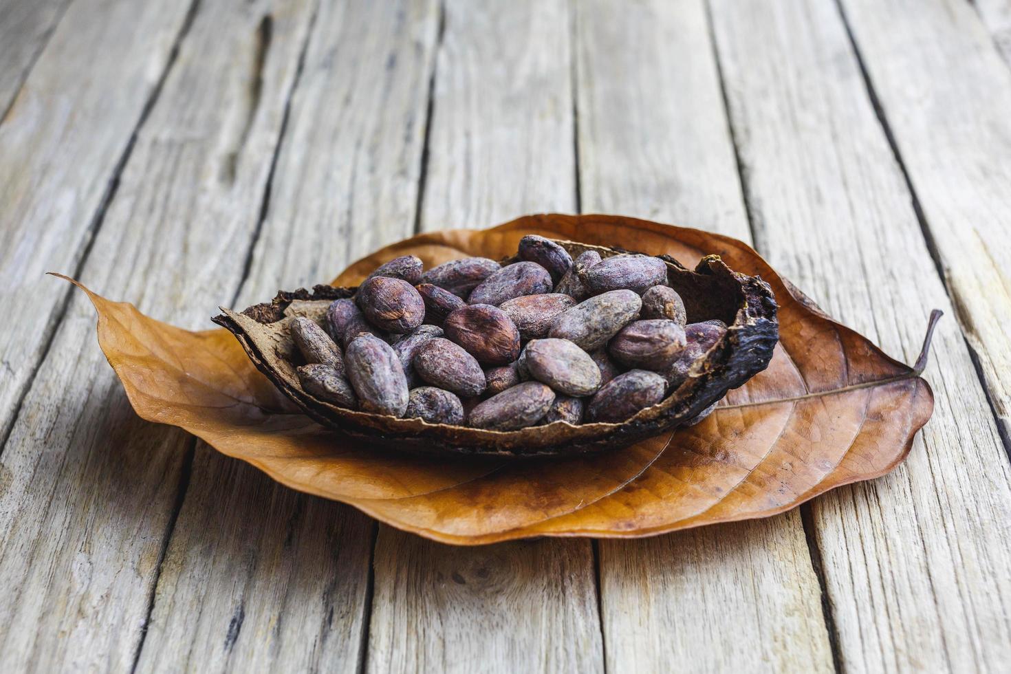 grano de cacao seco sobre mesa de madera foto