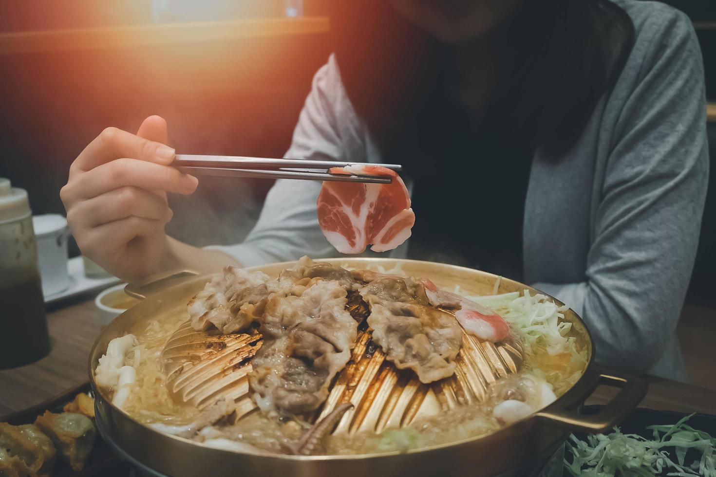 Asian woman eating yakiniku food Japanese version of Korean BBQ. Raw meat on a plate and grilled meat with sauce. Wagyu A5 japanese beef which considered as the best beef in the world photo