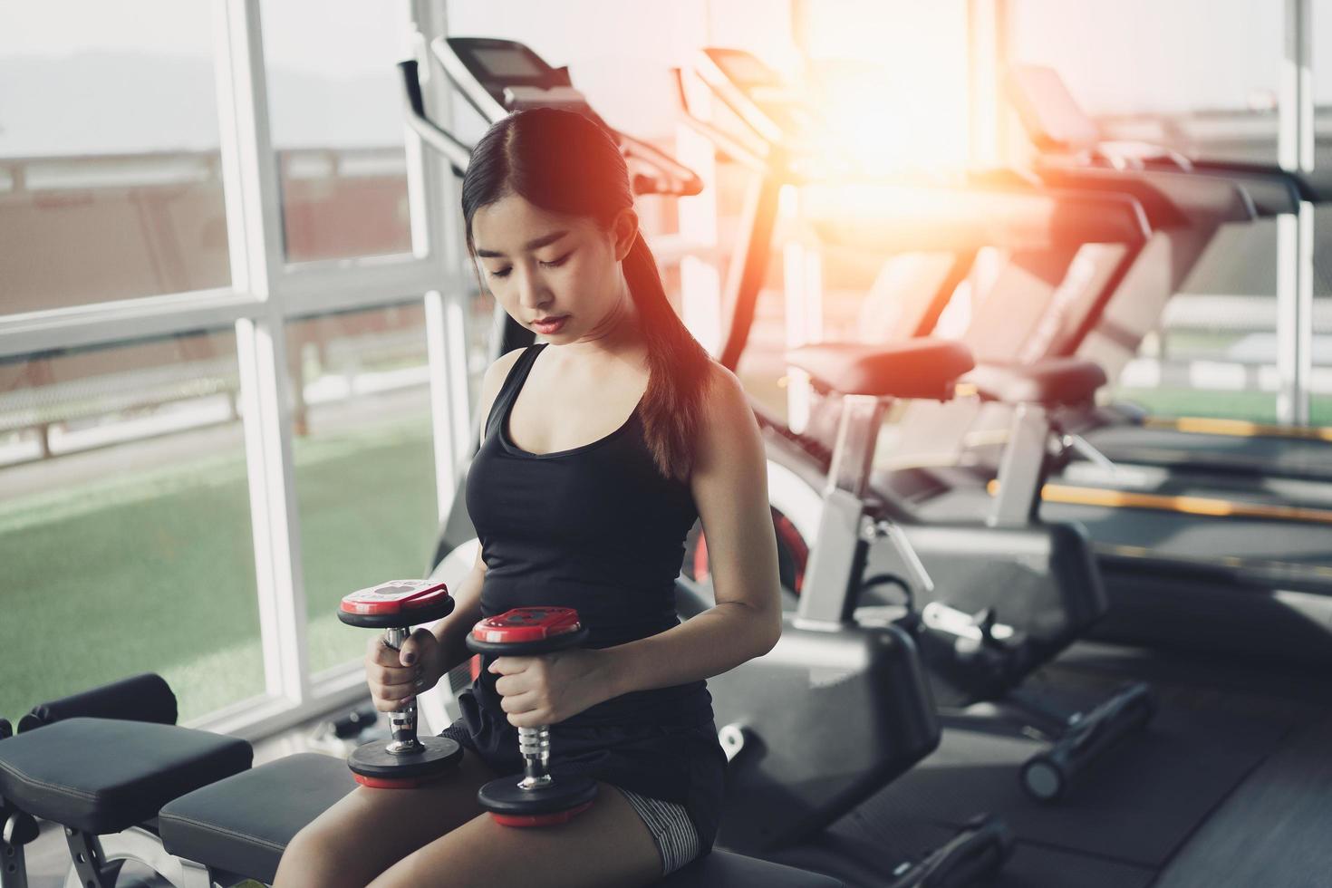 Asian fit sport woman working out in weights room at the gym. Sport woman fitness concept photo