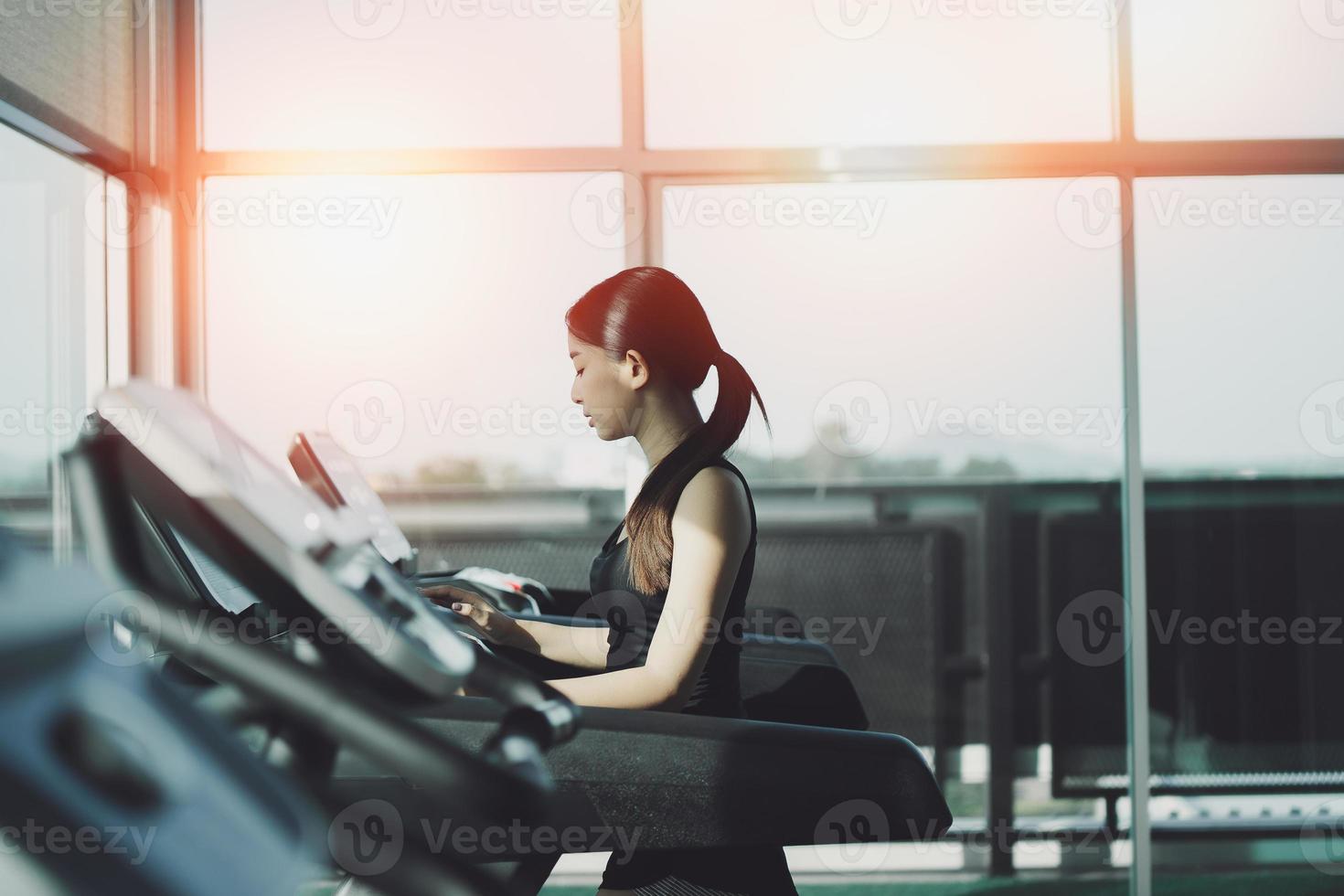 mujer deportiva asiática corriendo en cinta de correr en el gimnasio. entrenamiento cardiovascular. estilo de vida saludable, chico entrenando en el gimnasio. concepto de carrera deportiva foto