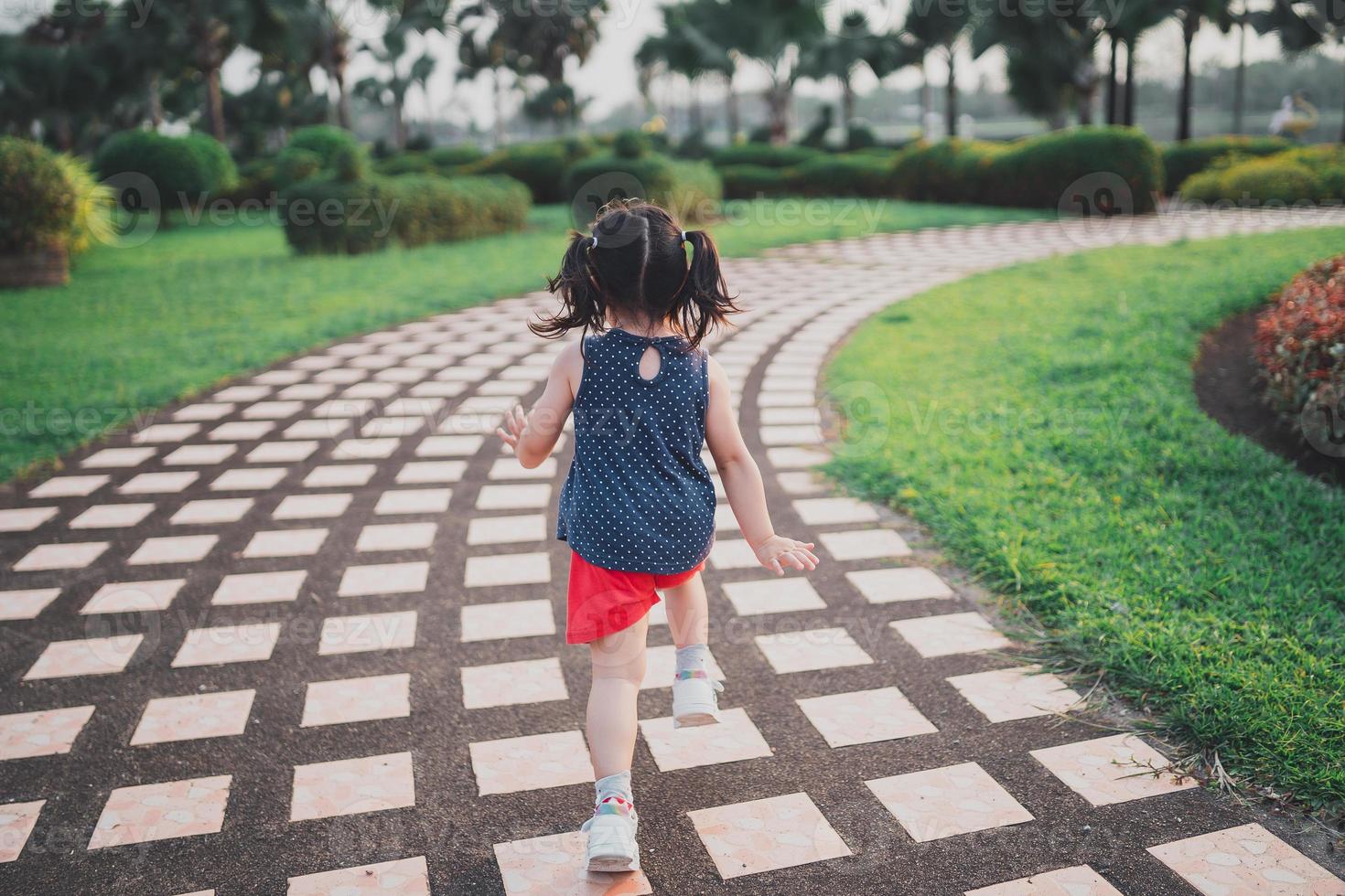 niña asiática bebé feliz sonriendo. niña corriendo al atardecer niña feliz sonriendo. niña corriendo al atardecer. linda niña corriendo en el jardín de juegos. foto