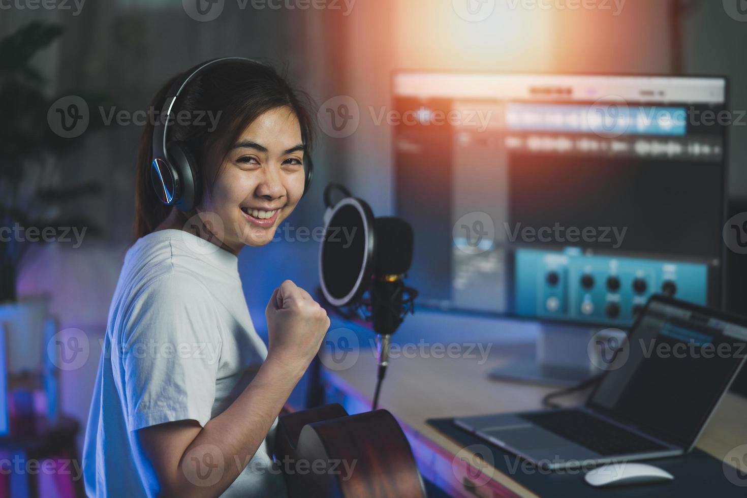 mujer asiática que usa auriculares y canta una canción, graba sonido con un micrófono y usa un programa de grabación de música por computadora. mujer ingeniera de sonido graba música. foto