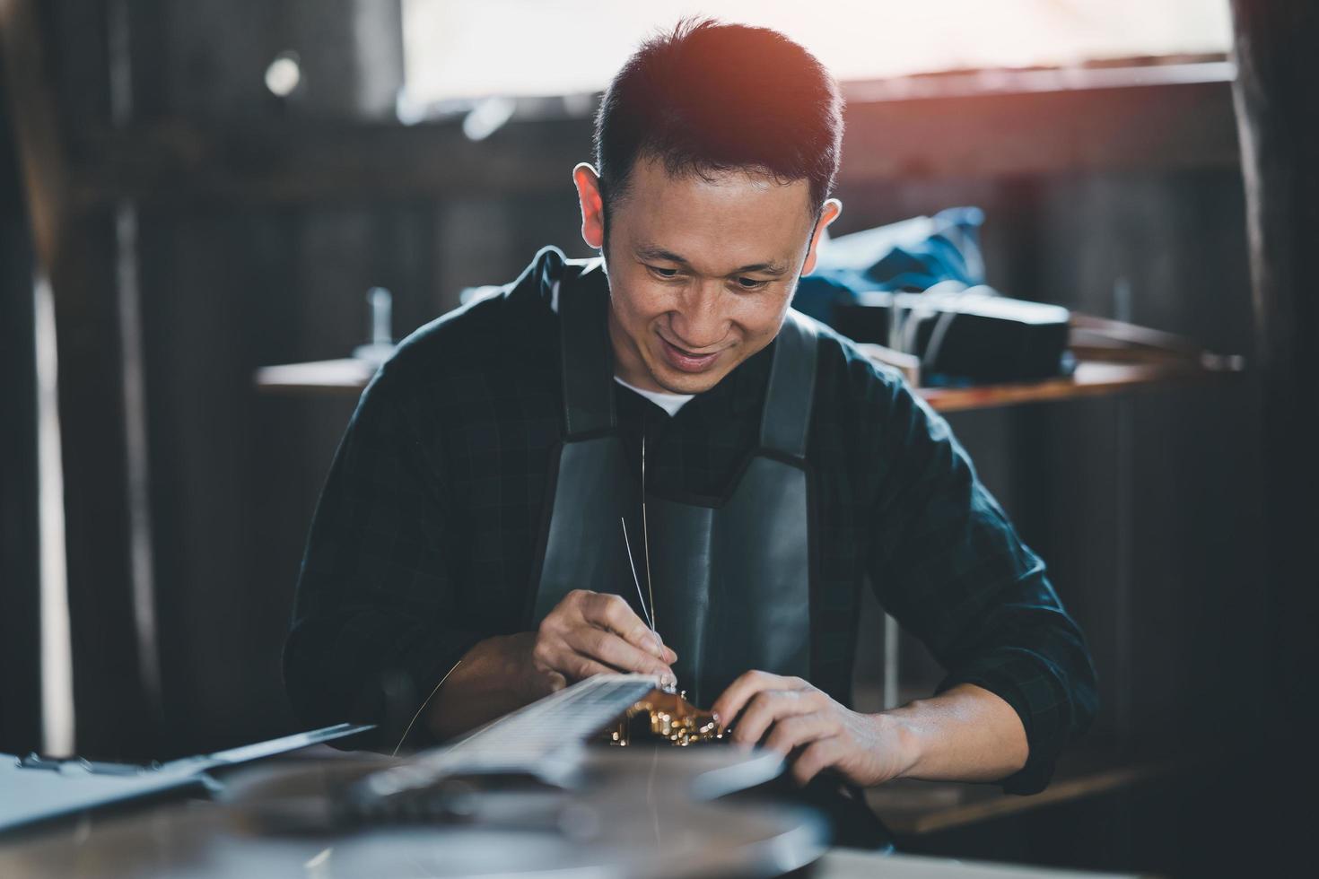 los fabricantes de guitarras ponen cuerdas de guitarra acústica después de hacer guitarras acústicas en una tienda de guitarras conceptuales, una tienda de guitarras hechas a mano. foto