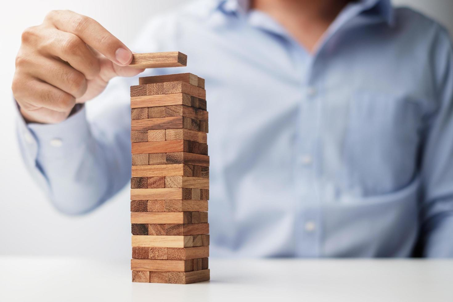 Businessman hand placing or pulling wooden block on the tower. Business planning, Risk Management, Solution and strategy Concepts photo