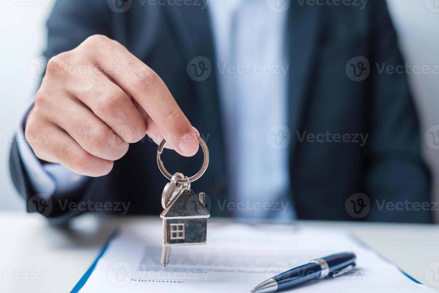 man holding home key during signing home contract documents. Contract agreement, real estate,  buy and sale and insurance concepts photo