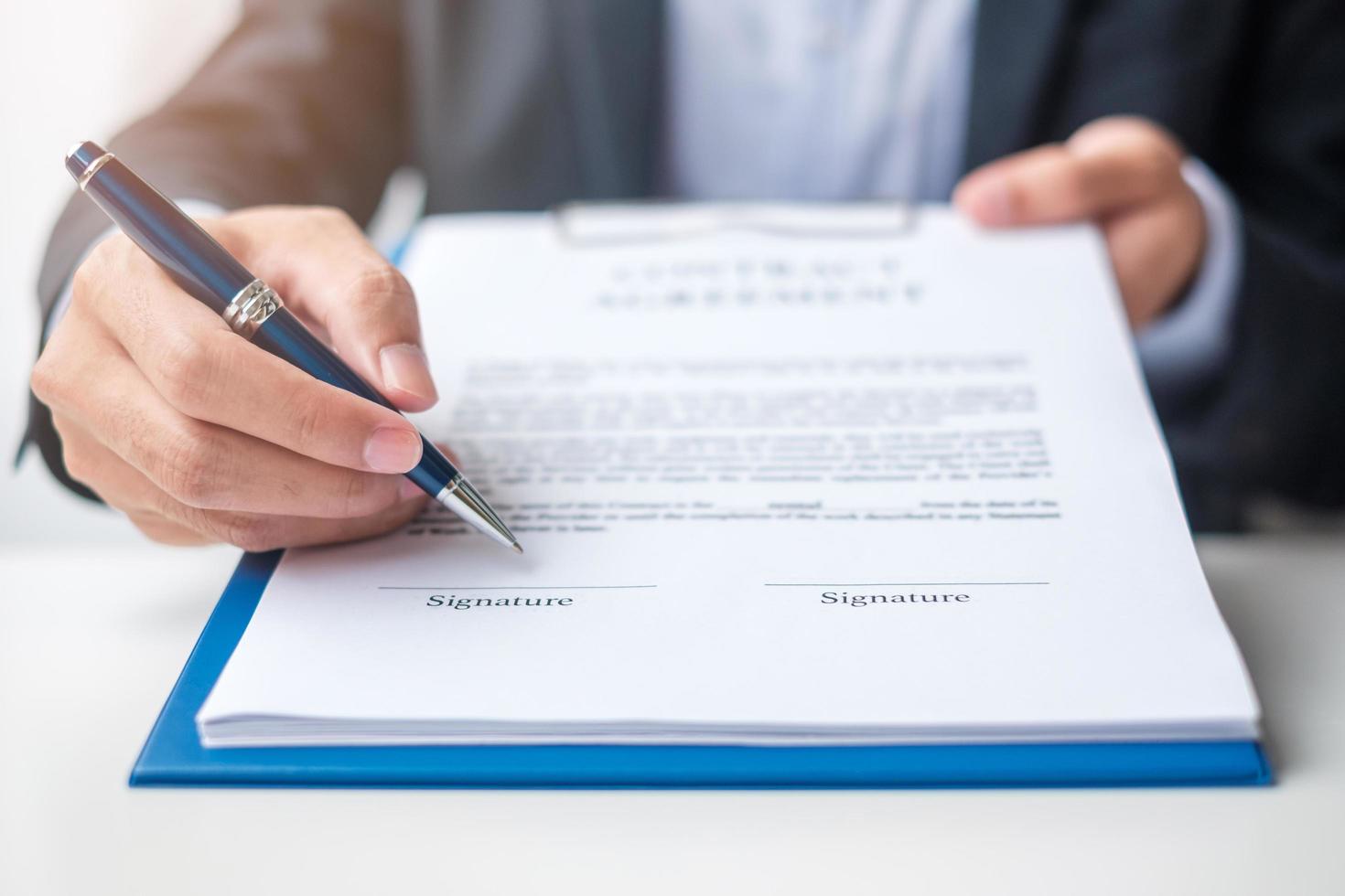 Businessman signing on contract documents after reading, man holding pen and approve on business report. Contract agreement, partnership and deal concepts photo