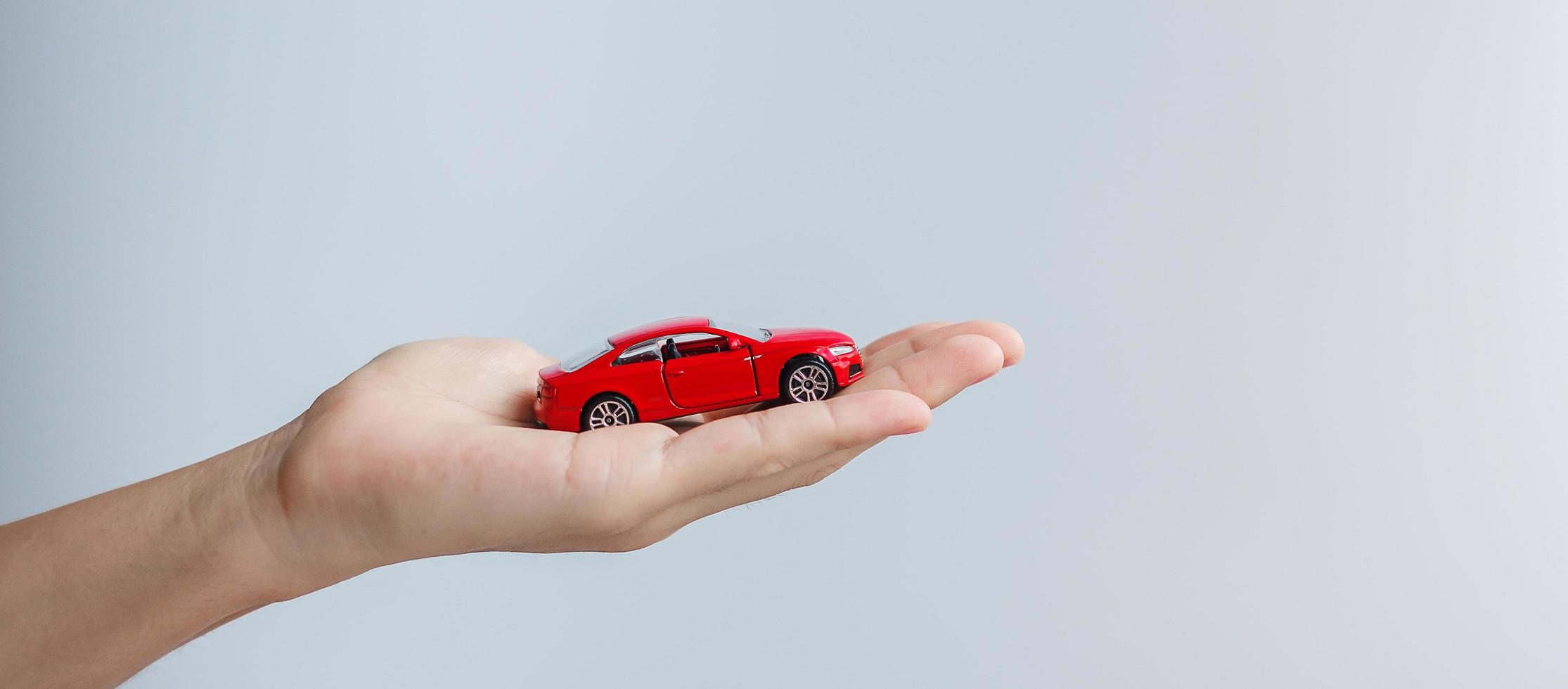 mano de hombre de negocios con juguete de coche rojo. seguro de automóvil, garantía, alquiler, concepto financiero, nuevo y de reparación foto
