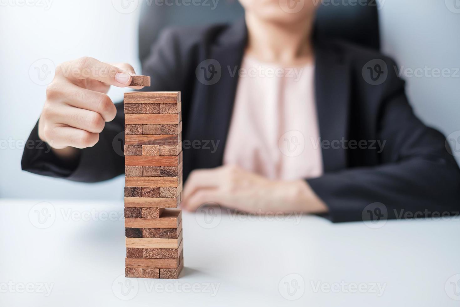 mano de empresaria colocando o tirando de un bloque de madera en la torre. conceptos de planificación empresarial, gestión de riesgos, solución y estrategia foto