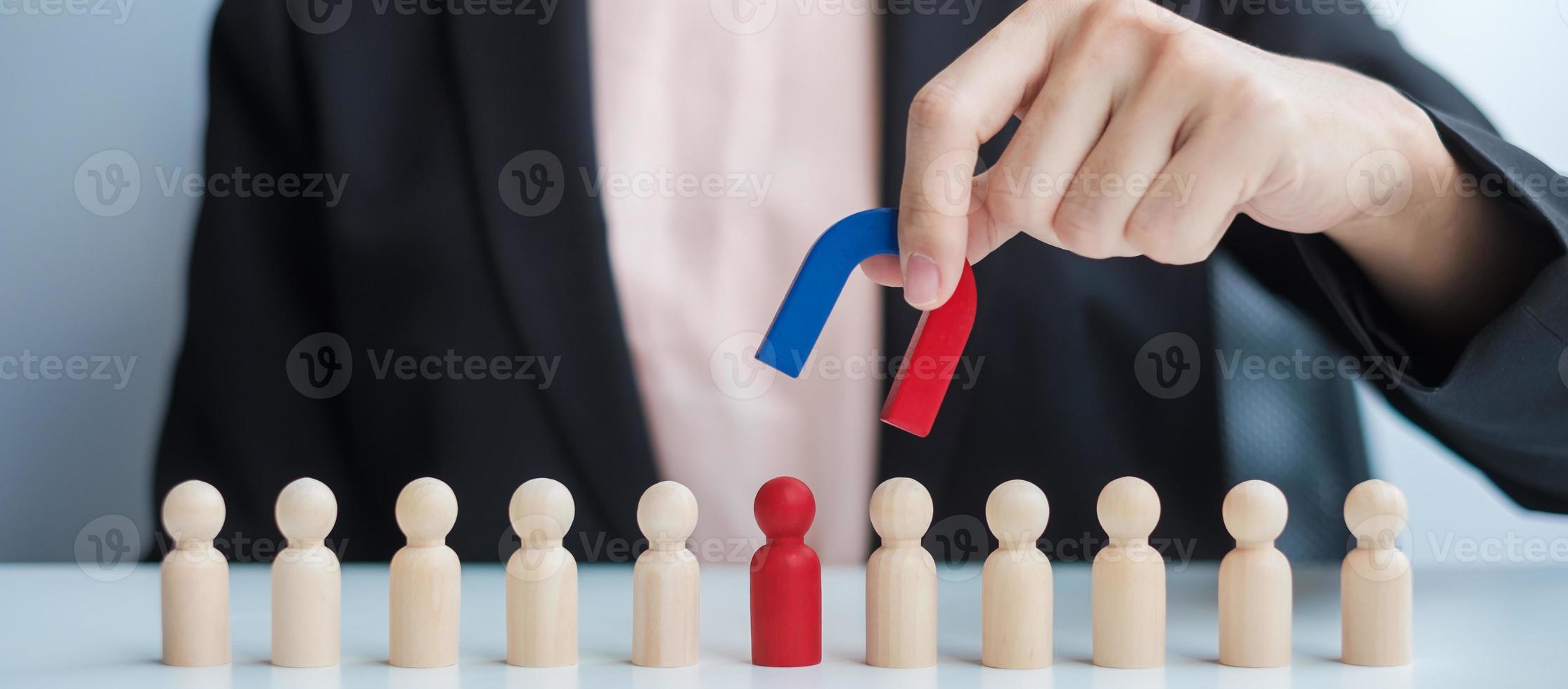 Business woman hand holding magnet and pulling man wooden figure from the crowd employee. Business, Human resource management, Recruitment, Teamwork, strategy, toxic people and leadership Concepts photo