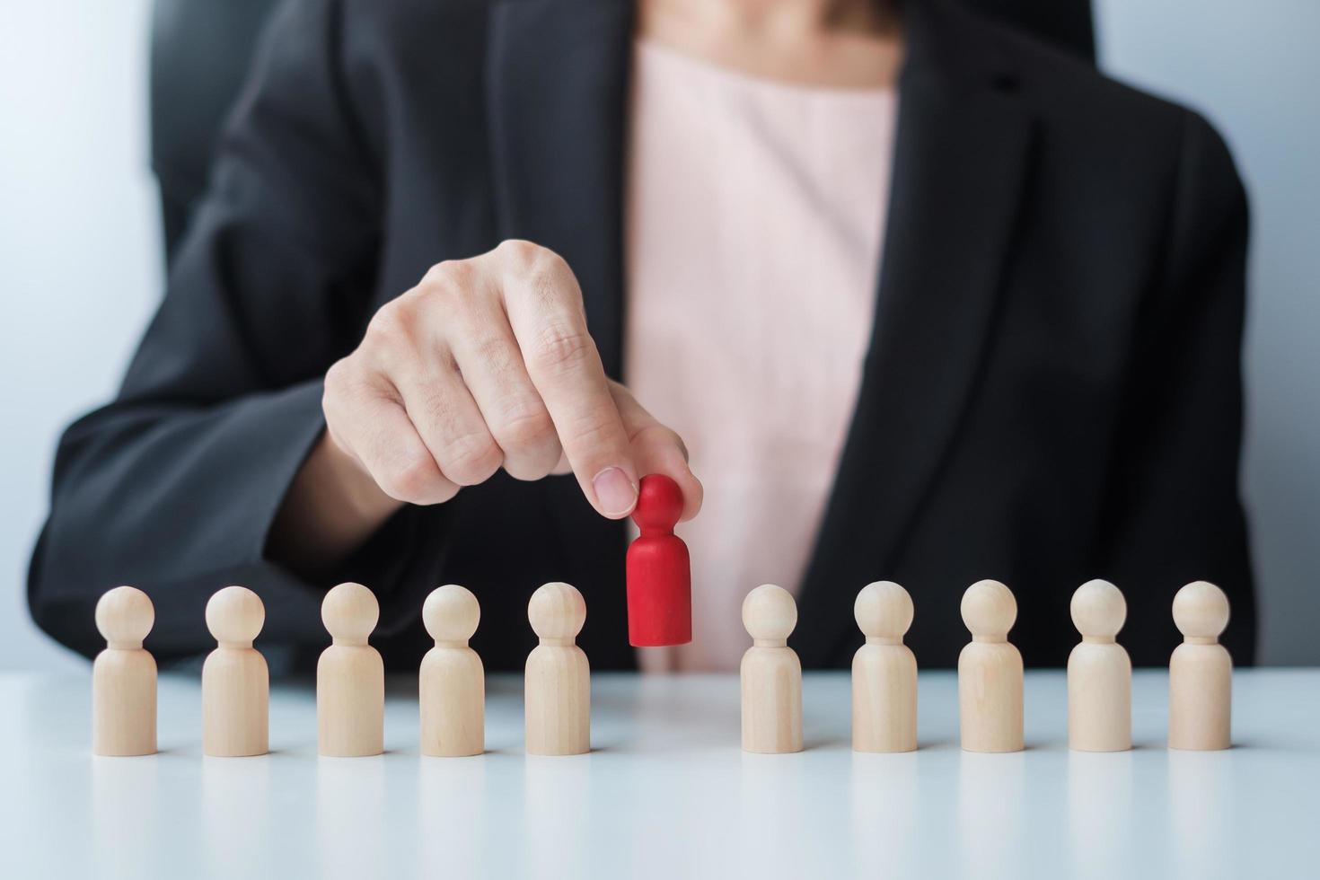 Businesswoman hand pulling leader man wooden from crowd of employees. Toxic People, Human resource management, Recruitment, Teamwork and leadership Concepts photo