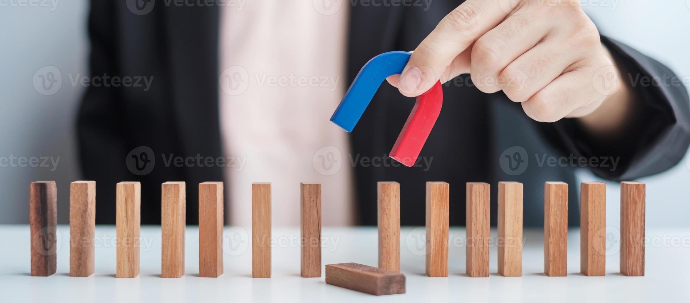 Business woman hand holding magnet and pulling man wooden figure from the crowd block. Business, Human resource management, Recruitment, Teamwork, strategy, toxic people and leadership Concepts photo