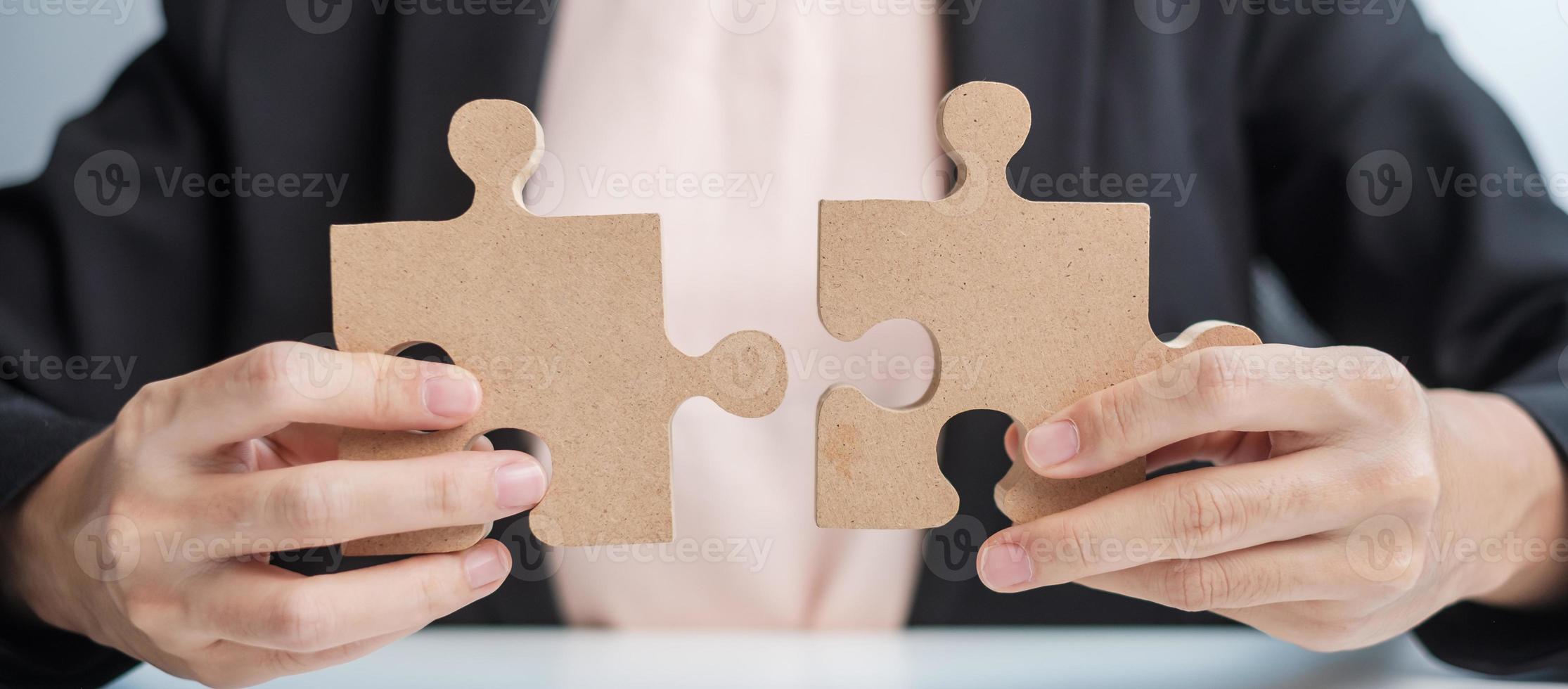 Woman connecting couple puzzle piece, wood jigsaw on table. Business solutions, mission, success, goals and strategy concepts photo