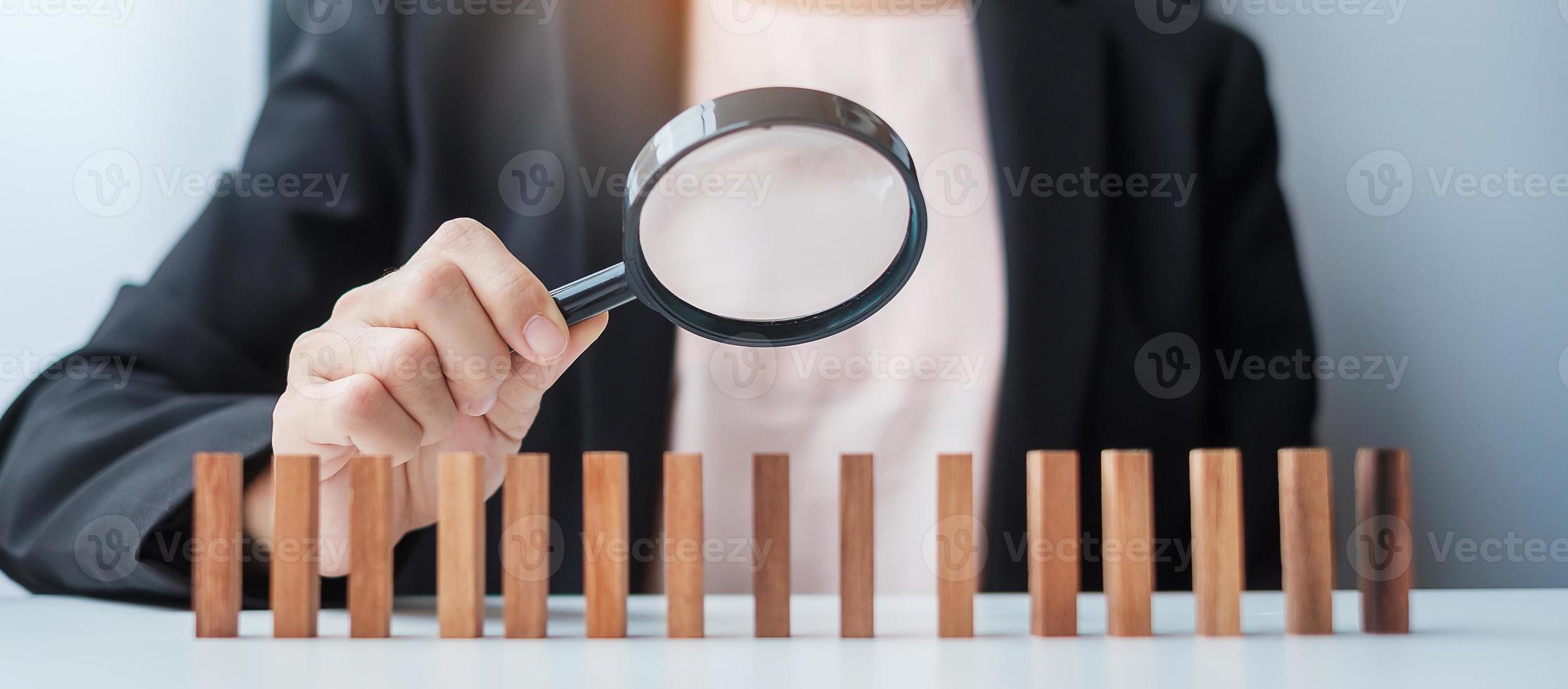 Businesswoman hand holding magnifying glass for recruiting leader man wooden from crowd of blocks .Human resource management, Recruitment, Teamwork, hiring and leadership Concepts photo