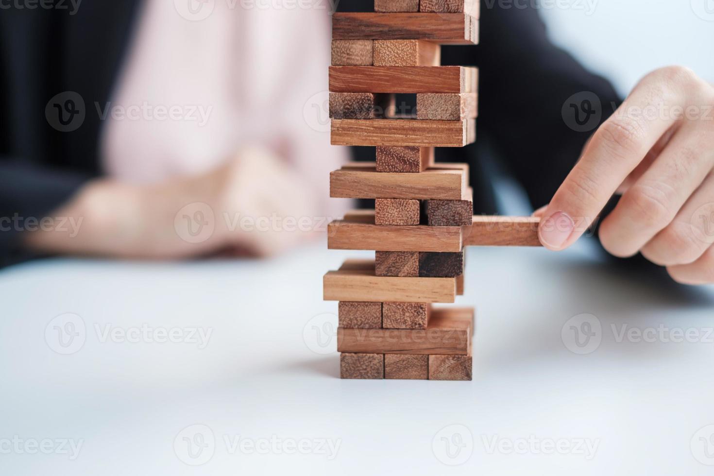 mano de empresaria colocando o tirando de un bloque de madera en la torre. conceptos de planificación empresarial, gestión de riesgos, solución y estrategia foto