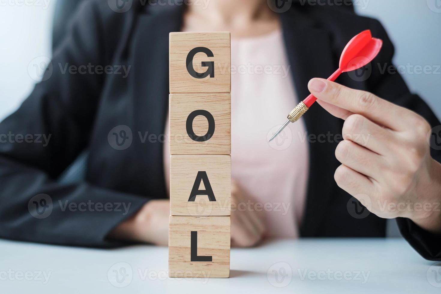 Hand holding red dart over Goal block. target, aim, objective, leadership, Business and marketing concept photo