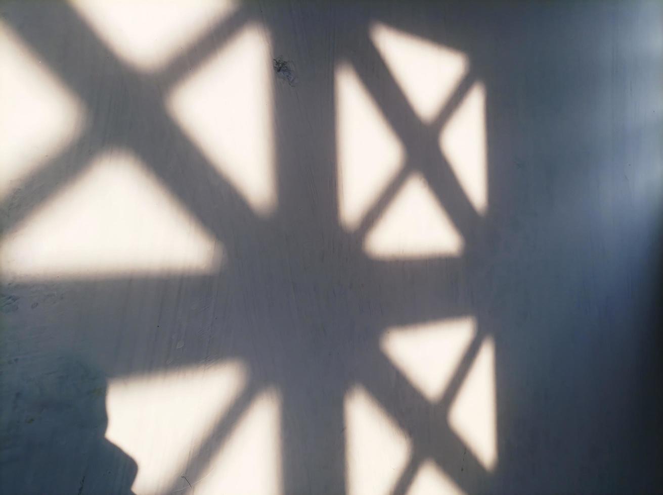 una foto de una pared blanca opaca y la luz del sol por la mañana formando un patrón. patrón de luz solar borrosa