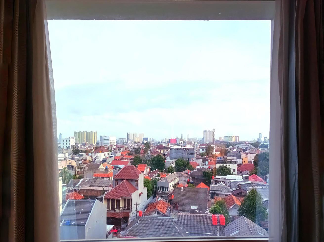 foto de casas muy densamente pobladas con varios colores en la ciudad capital de jakarta, indonesia, debido a la migración de la población vista desde la ventana de cristal del hotel