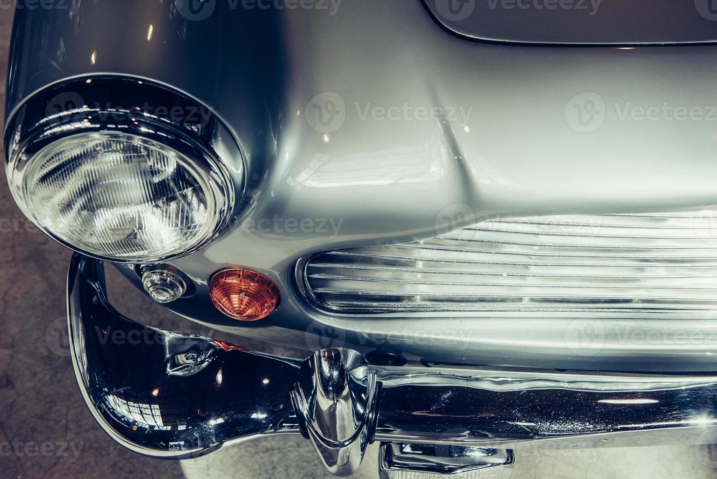 closeup of the headlights and front bumper on  vintage automobile photo