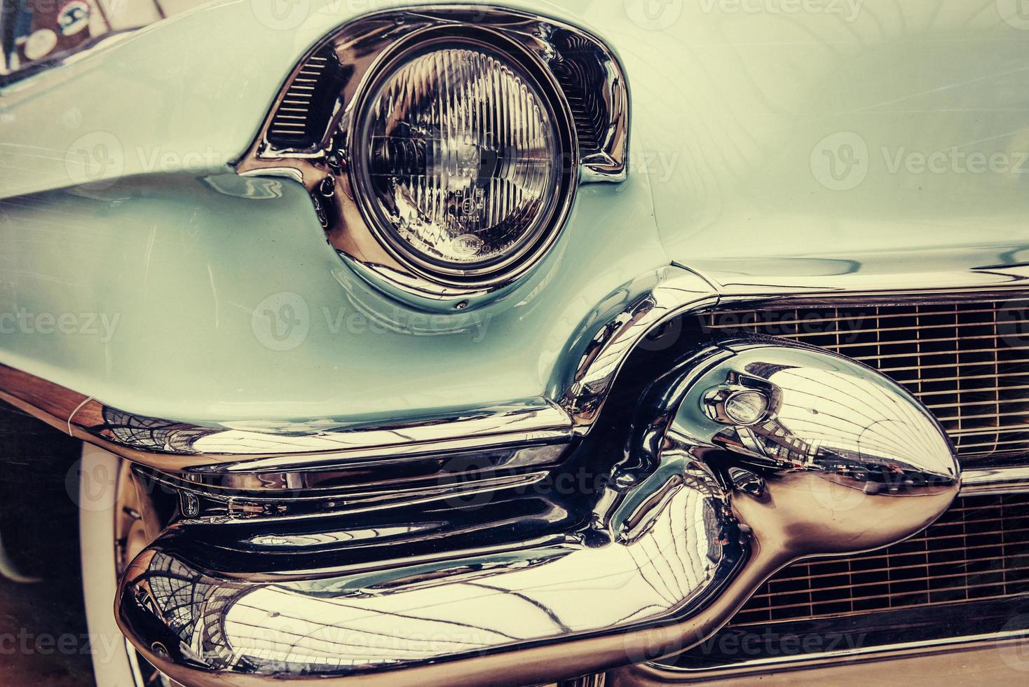 closeup of the headlights and front bumper on  vintage automobile photo