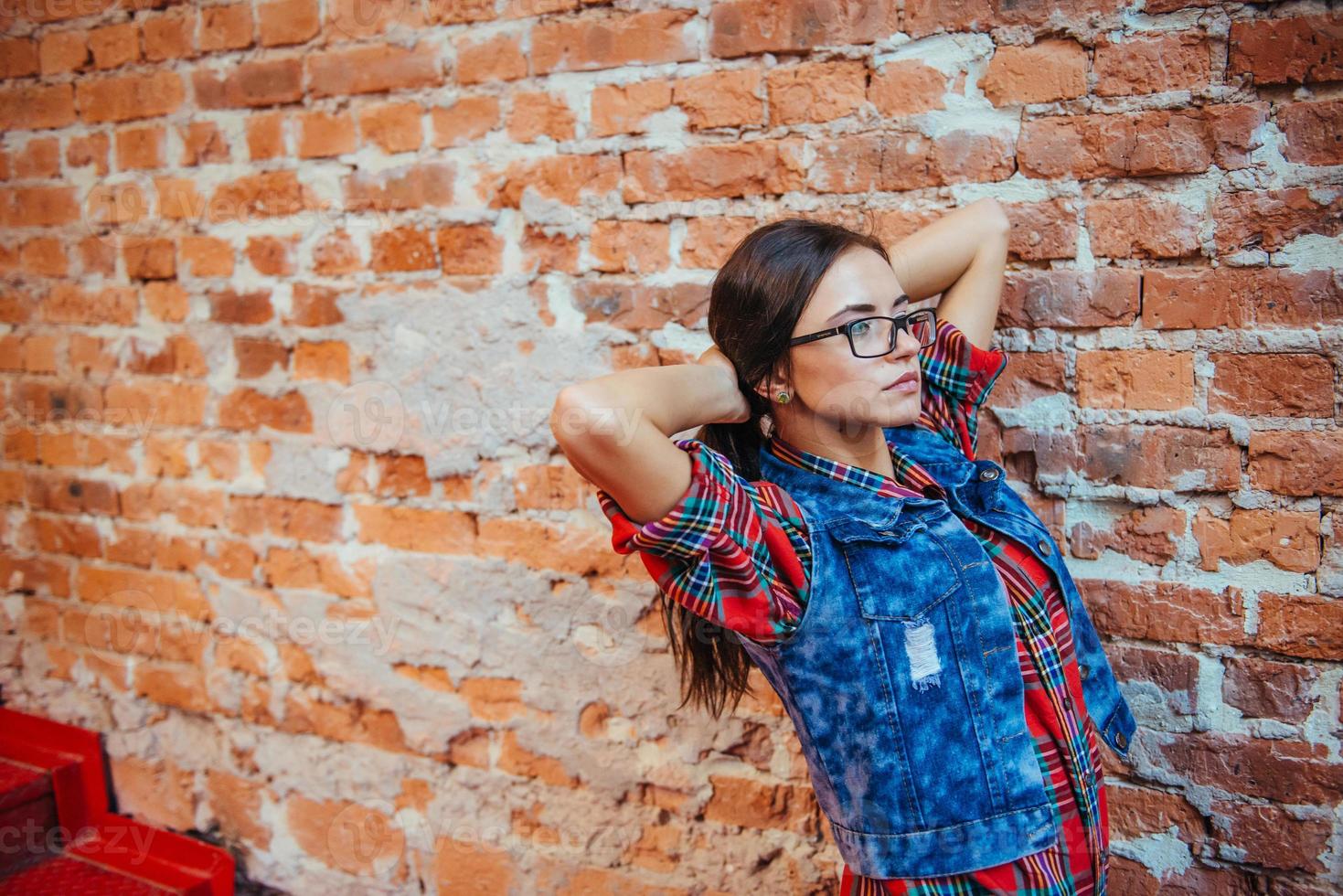 Beautiful young woman stands near the old brick wall. Youth styl photo