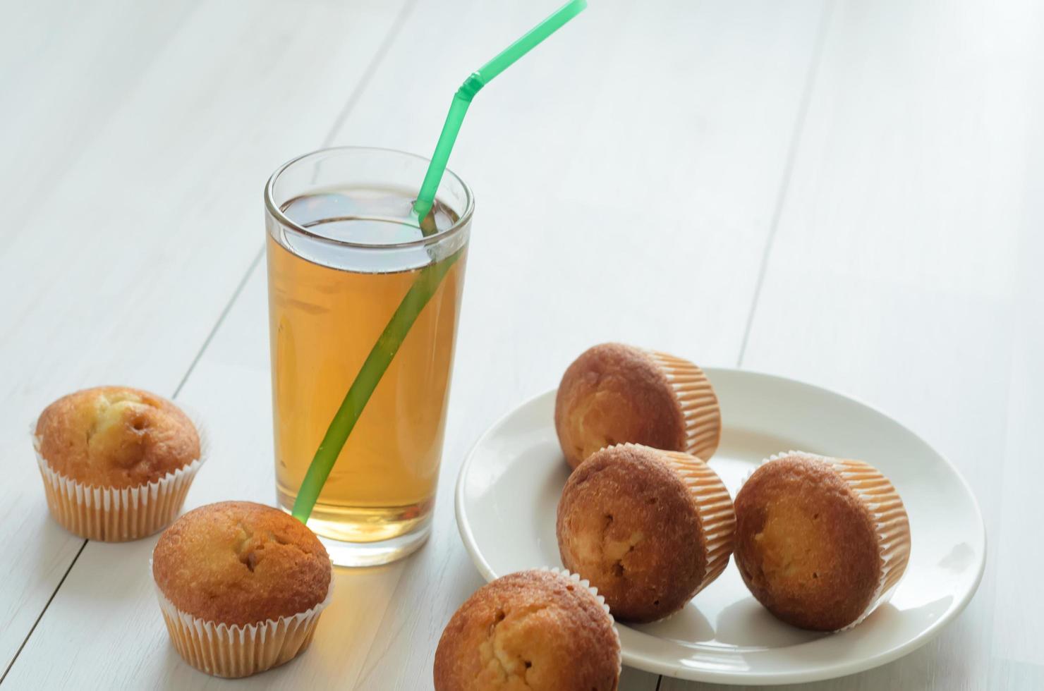 un vaso de jugo de pomelo de manzana, tres panecillos en un plato y más tres panecillos dulces... desayuno fresco en la mañana. foto