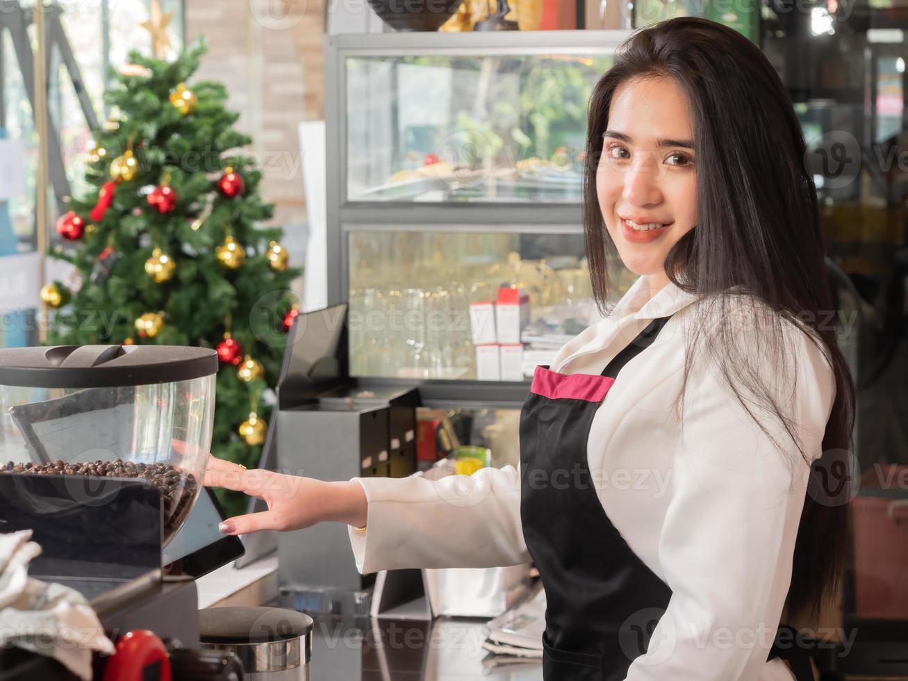 bella mujer asiática propietaria de una cafetería y una barista parada en el bar y revisando los pedidos de los clientes en línea desde una computadora en la cafetería foto