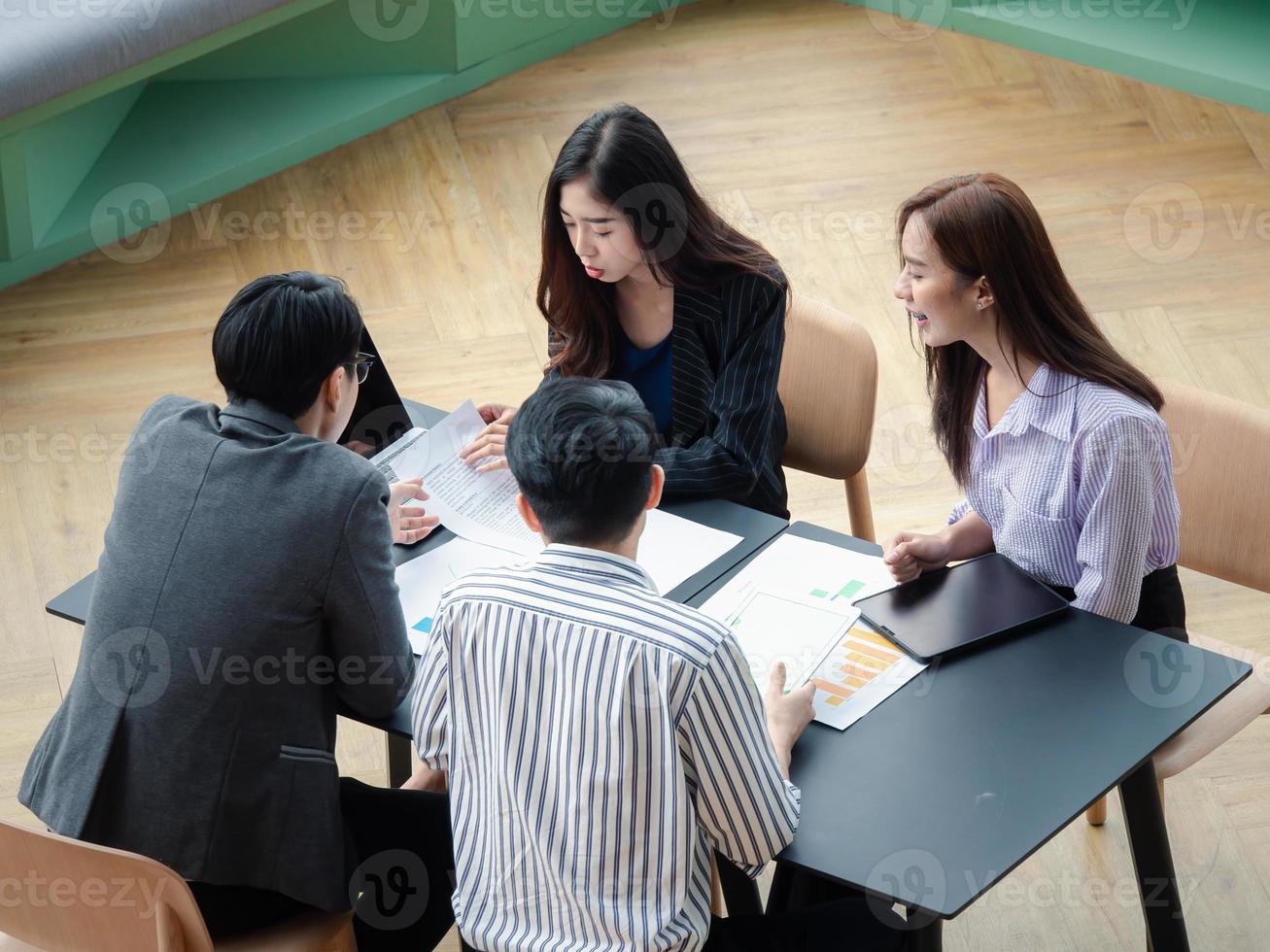 grupo de jóvenes equipos de negocios discuten algo mientras se sientan juntos en la mesa del espacio de trabajo conjunto, planifican la estrategia y la lluvia de ideas, los colegas piensan en el concepto foto