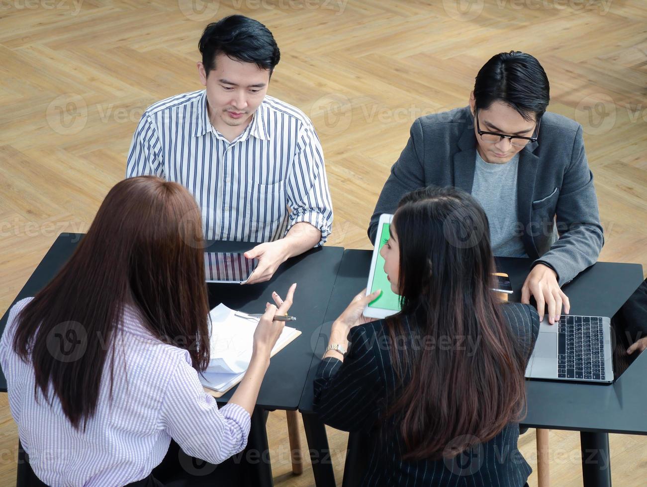 grupo de jóvenes equipos de negocios discuten algo mientras se sientan juntos en la mesa del espacio de trabajo conjunto, planifican la estrategia y la lluvia de ideas, los colegas piensan en el concepto foto