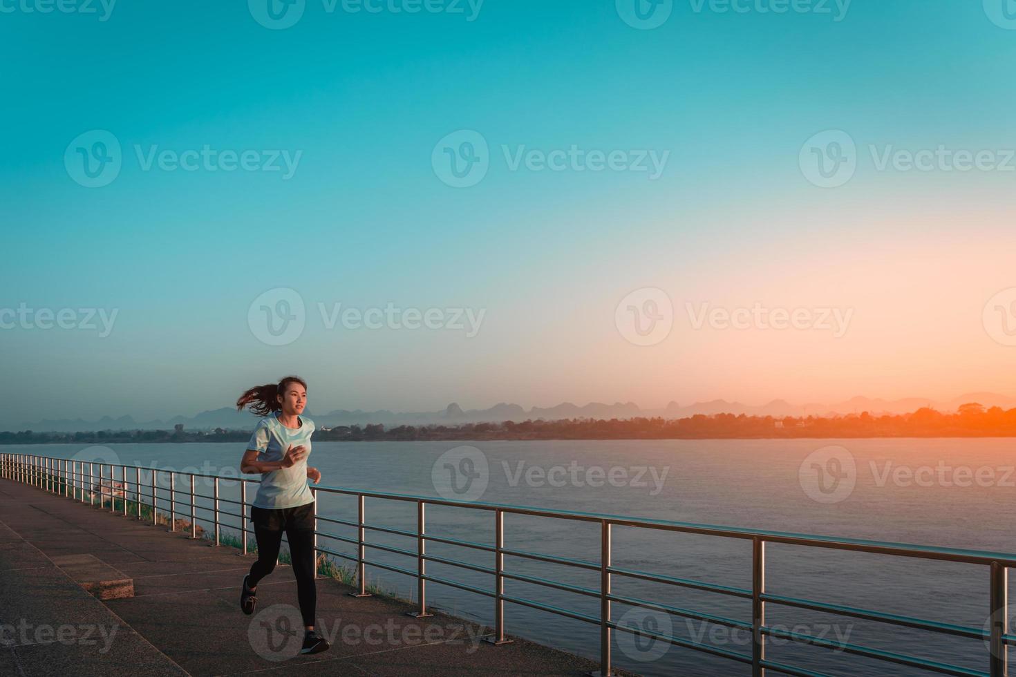 Woman running on street with a view of river in the morning. photo