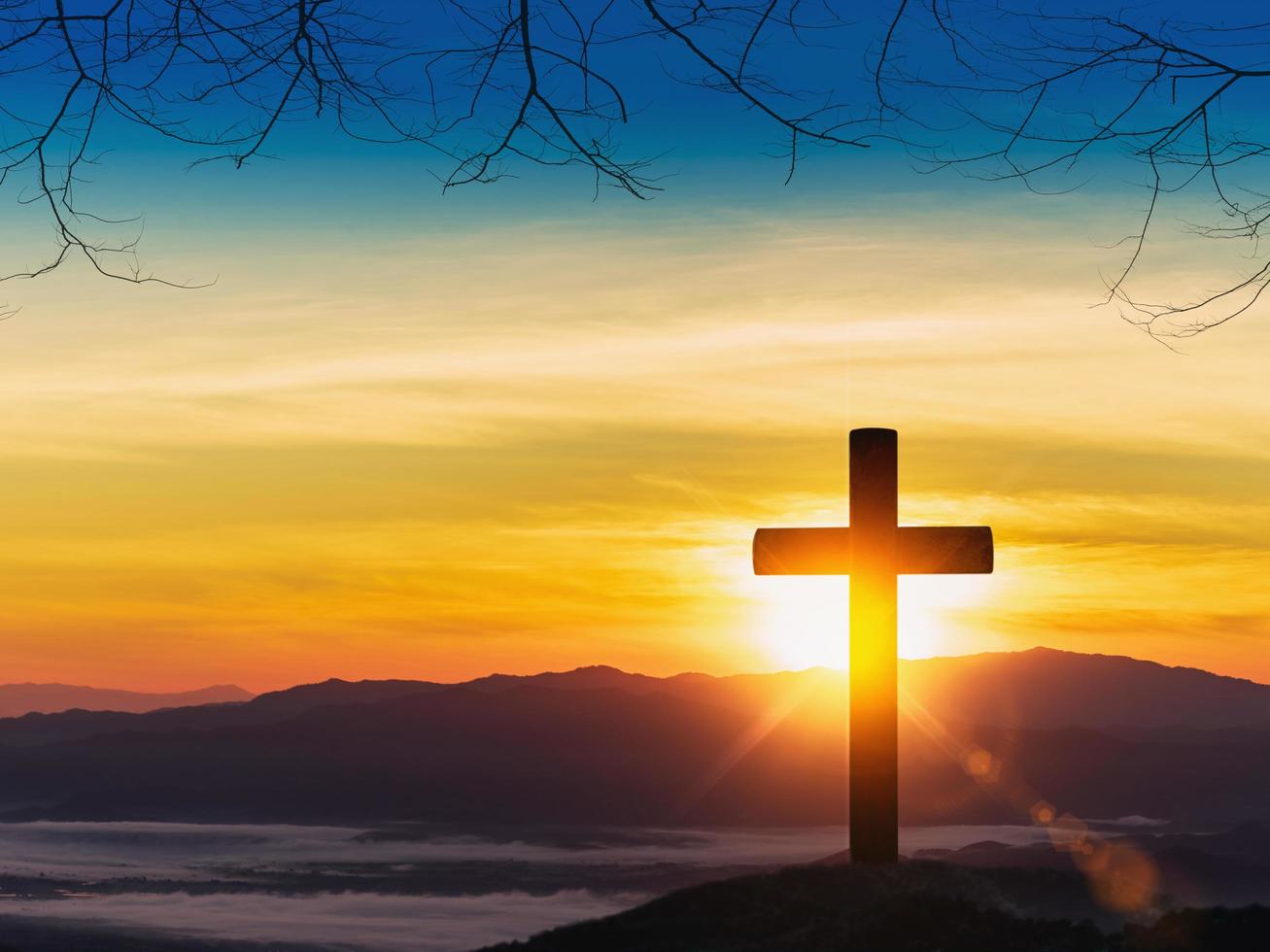 Silhouette of cross on mountain sunset background. photo