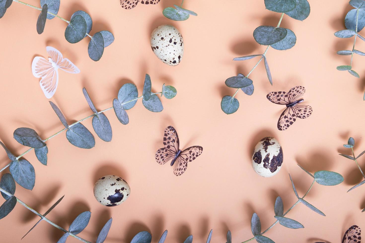 Pattern of Easter eggs, eucalyptus, butterflies and beads. Trendy flat lay composition on color background photo